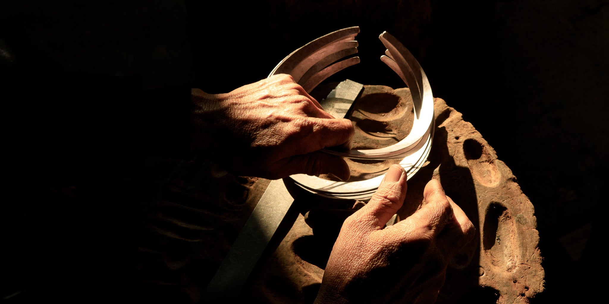 Mains d’un artisan karen façonnant un bracelet en argent dans l’atelier – Itsara