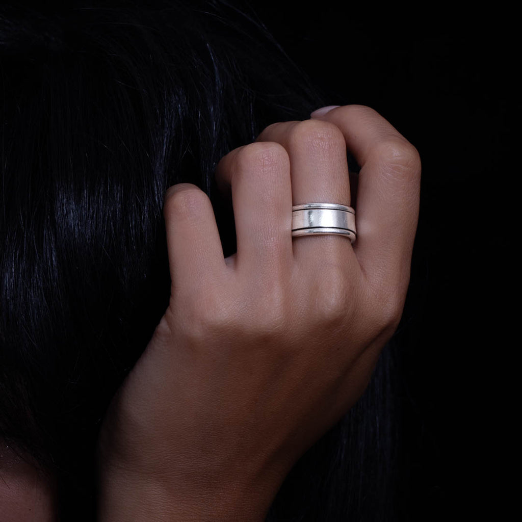 Bague contemporaine artisanale en argent massif pour femme, alliant sobriété et élégance. Son design unique permet de révéler un aspect travillé ou lisse selon sa position sur le doigt, ajoutant une touche de personnalité.