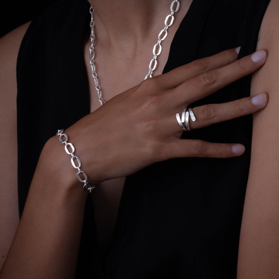 Femme portant un bracelet chaine en argent N°11 entièrement fait à la main par des artisans ainsi qu'une bague en argent contemporaine N°26 artisanale en argent massif pour femme - Itsara bijoux