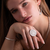 Femme portant la bague artisanale en argent massif ethnique N°20 avec un plateau poinçonné à main levée, motifs de fleurs et de montagnes - Itsara bijoux