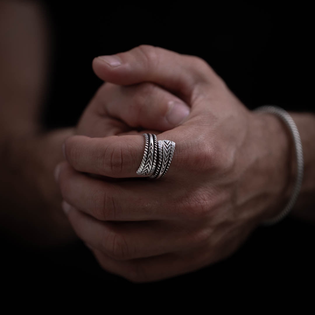 bague artisanale en argent massif présente un design affirmé. Un fil épais en argent est encadré par deux fils torsadés, légèrement aplatis aux extrémités et patinés pour un effet visuel encore plus marquant. Une pièce unique réalisée entièrement à la main