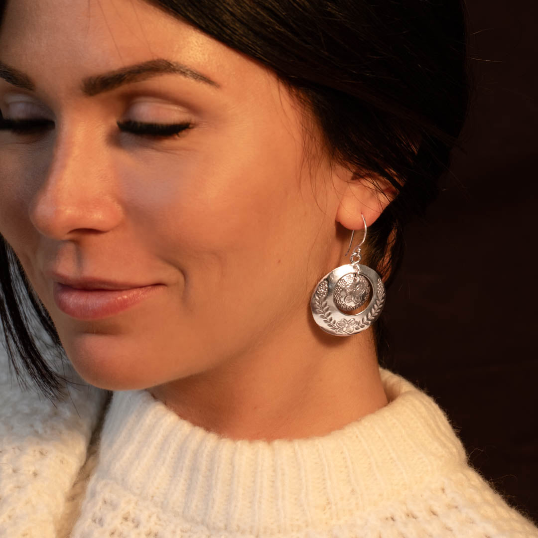 Modèle féminin portant des boucles d'oreilles N°75 en argent massif ethnique représentant des fleurs et des papillons fait à la main - Itsara Bijoux