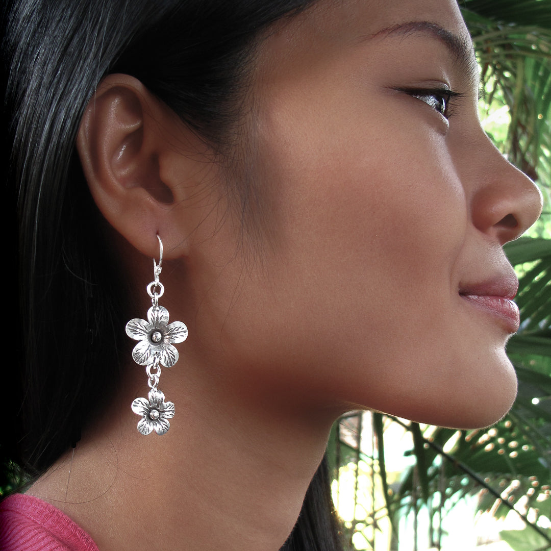 Boucles d'oreilles en argent Fleurs N°21 composées de deux fleurs en argent massif réalisées entièrement à la main par les artisans de la tribu karen, portées par une femme - Itsara Bijoux