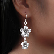 Boucles d'oreilles en argent Fleurs N°21 composées de deux fleurs en argent massif réalisées entièrement à la main par les artisans de la tribu karen, portées par une femme - Itsara Bijoux