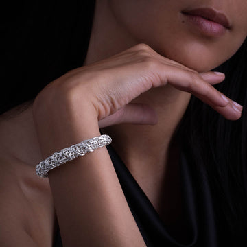 femme portant un bracelet en argent massif  fait à la main en tressage ajouré de fils d'argent. Le travail de l'artisan.e apporte beaucoup de relief à ce bracelet original et féminin.