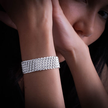 modèle féminin portant un bracelet en argent massif réalisé en un tressage régulier et serré de fils d'argent massif créant ainsi une belle matière en relief. 