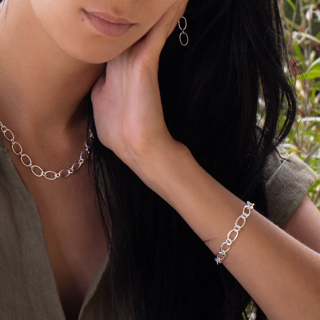 Modèle féminin portant un bracelet en chaine N°23 en argent massif artisanale fait à la main avec un collier et des boucles d'oreilles du même style - Itsara Bijoux