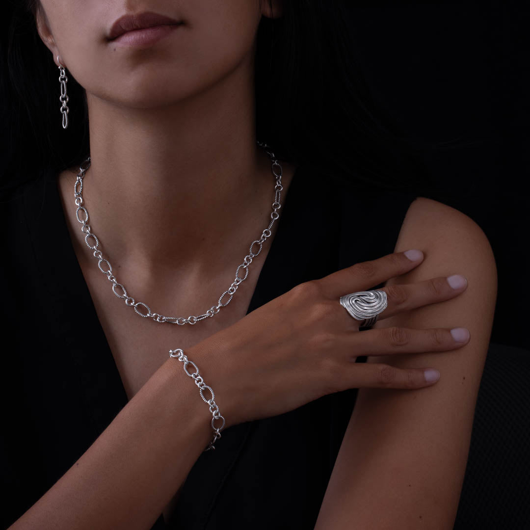 Femme portant un haut noir et des bijoux dont un bracelet chaine N°24 en argent massif fabriqué entièrement à la main ainsi qu'un collier chaine en argent massif - Itsara Bijoux