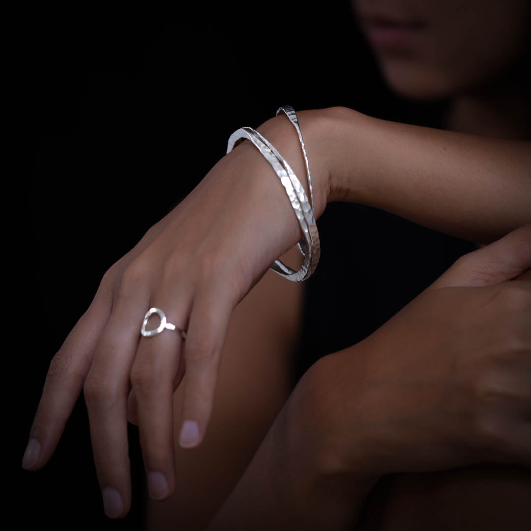 Main féminine portant un bracelet N°36 en argent massif fait entièrement à a
la main par des artisans à porter seul, ou à empilé avec plusieurs pièces - Itsara Bijoux