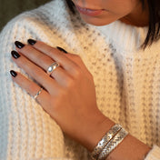 Femme portant un pull en laine blanc avec des bijoux dont un bracelet N°53 et N°38 en argent massif tressé fait à la main - Itsara Bijoux