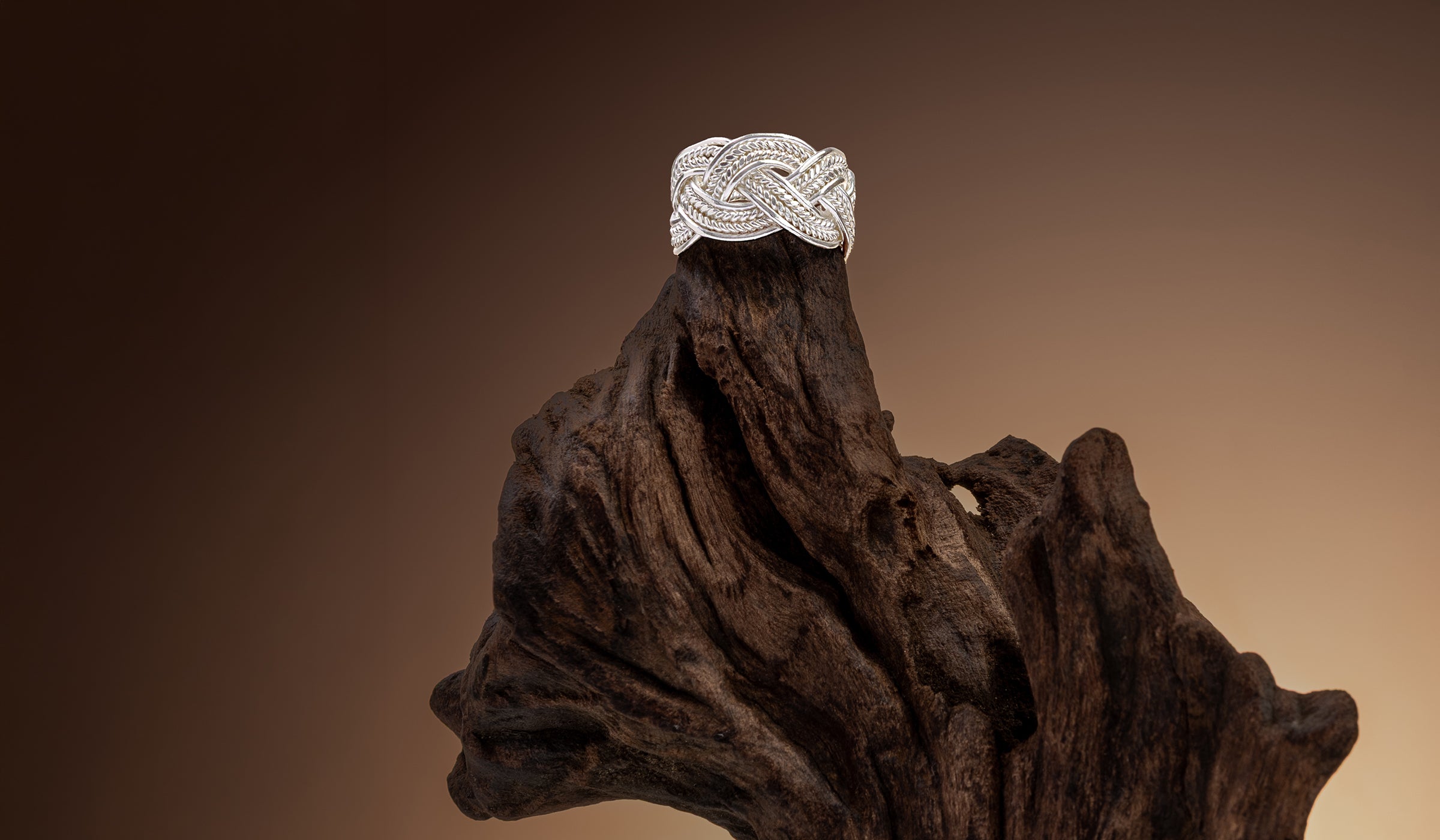 Bague tressée en argent massif posée sur du bois flotté – Itsara