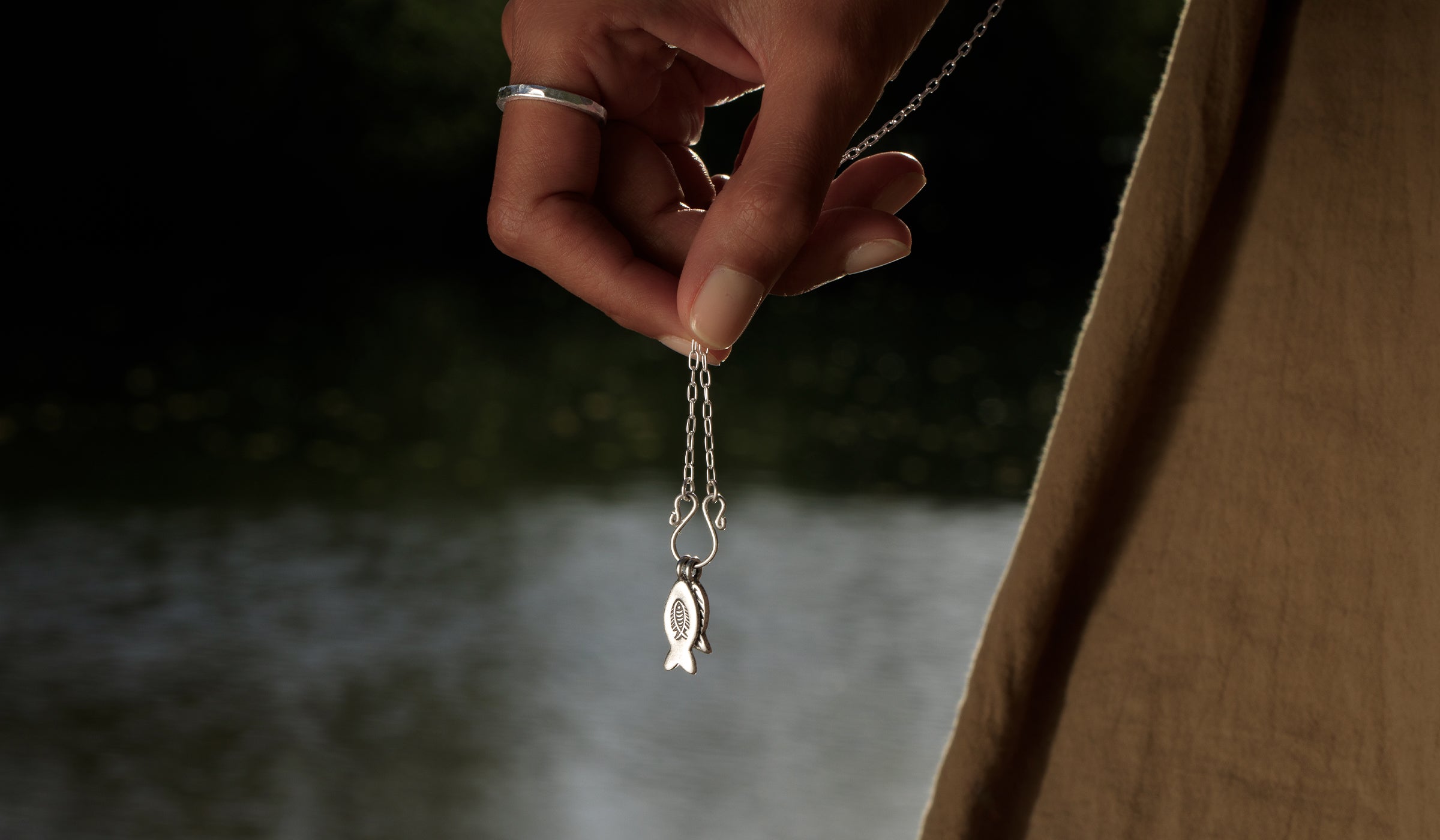 Pendentif poissons en argent sur chaîne fine, tenu à la main – Itsara