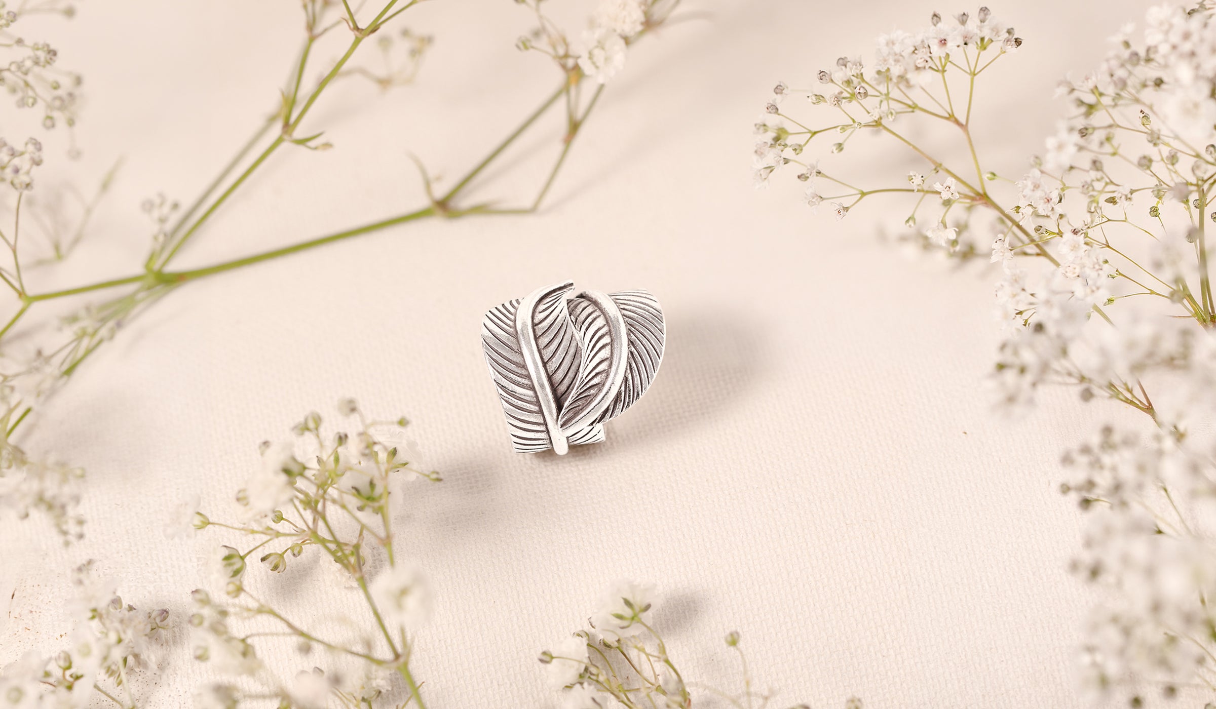 Bague à feuilles en argent massif patiné posée parmi des fleurs de gypsophile – Itsara