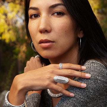 Femme portant une grande bague artisanale en argent massif avec un motif en relief, bijou ethnique chic au style protecteur