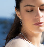 "Petites boucles d'oreilles en argent massif contemporaines N°17, artisanales et pendantes, symbolisant l'infini. Leur design léger et contemporain en fait un accessoire intemporel - Itsara bijoux