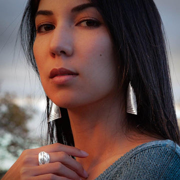 Longues boucles d'oreilles en argent massif pour femme, artisanales et contemporaines, de forme triangulaire. Leur design graphique et leurs angles courbés reflètent magnifiquement la lumière.