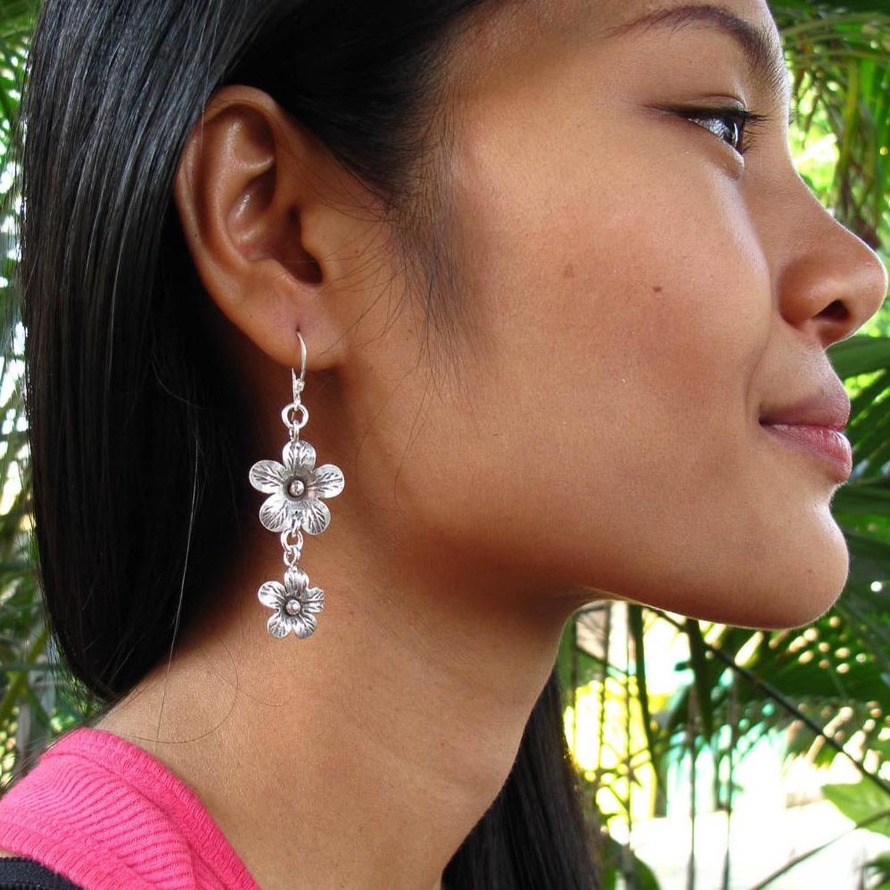 Boucles d'oreilles en argent Fleurs N°21 composées de deux fleurs en argent massif réalisées entièrement à la main par les artisans de la tribu karen, portées par une femme - Itsara Bijoux