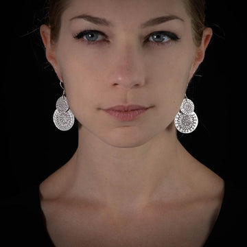 Boucles d'oreilles en argent Fleurs N°48 fabriquées à la main, composées de deux disques en argent massif avec des motifs fleuris, portées par une femme - Itsara Bijoux