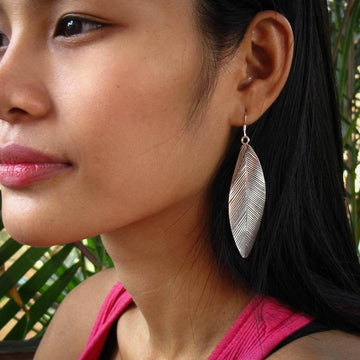 Les longues boucles d'oreilles en argent pour femme Itsara Bijoux présentent des stries patinées qui évoquent la beauté des plumes et des feuilles. Leur courbure délicate accentue chaque mouvement.
